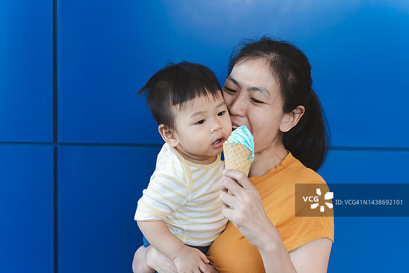 蓝色背景下吃冰淇淋的母子图片素材