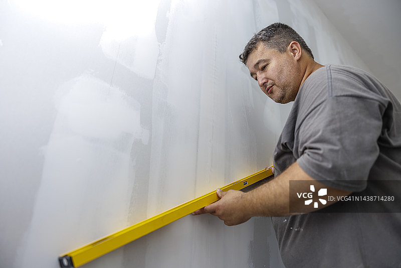 在新房子里用建筑水平仪测量墙壁图片素材