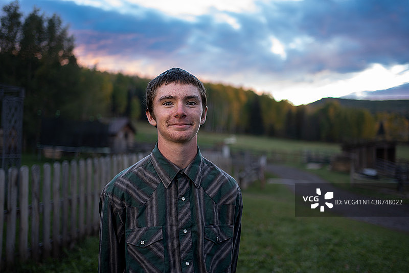 科罗拉多州西南部，Telluride附近牧场上的青少年农场男孩在秋季壮观的彩色日落下的画像图片素材