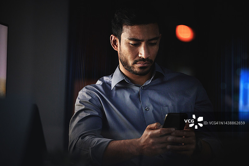 商务男士，在黑暗的房间里，员工正在使用手机处理文本和在社交媒体应用程序上滚动。企业商务人士在线忙于电子邮件的移动互联网、网络和技术图片素材