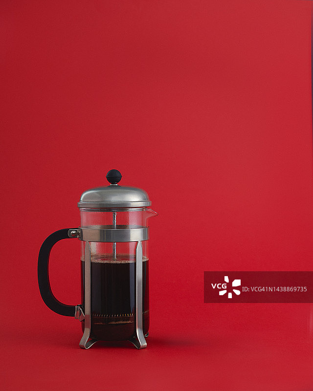 红色背景上的咖啡压滤壶图片素材