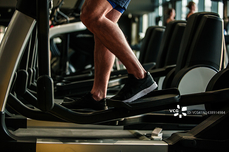 男运动员在健身房椭圆机上训练图片素材