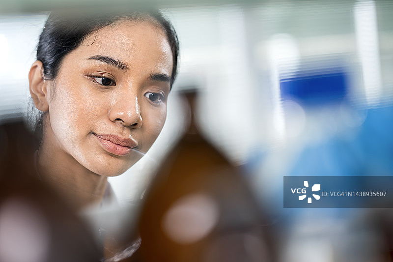 农业产品安全分析测试：亚洲女科学家在实验室分析化学溶液样品图片素材