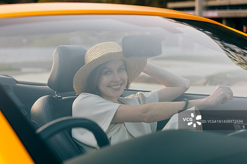 坐在车里的年轻女人，透过窗户看图片素材