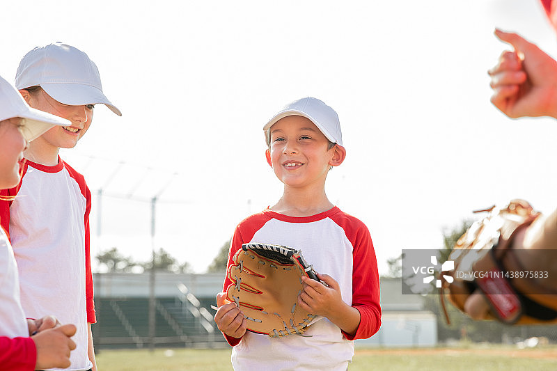 可爱的小男孩在少儿棒球比赛中与队友交谈时微笑图片素材