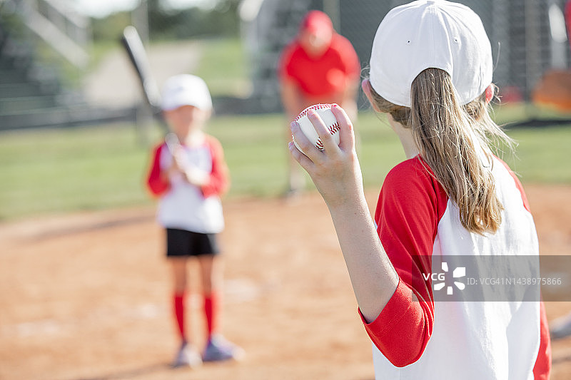 小女孩在少儿棒球比赛中投球图片素材