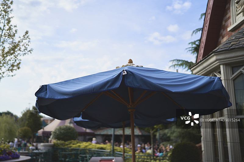 晴天旅游景点：玻璃窗建筑外的蓝色遮阳伞图片素材