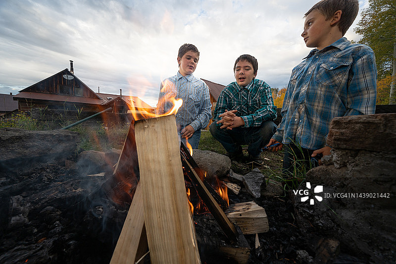 三个年轻的农家兄弟在科罗拉多州特柳赖德附近山区家园后面的森林里享受篝火图片素材