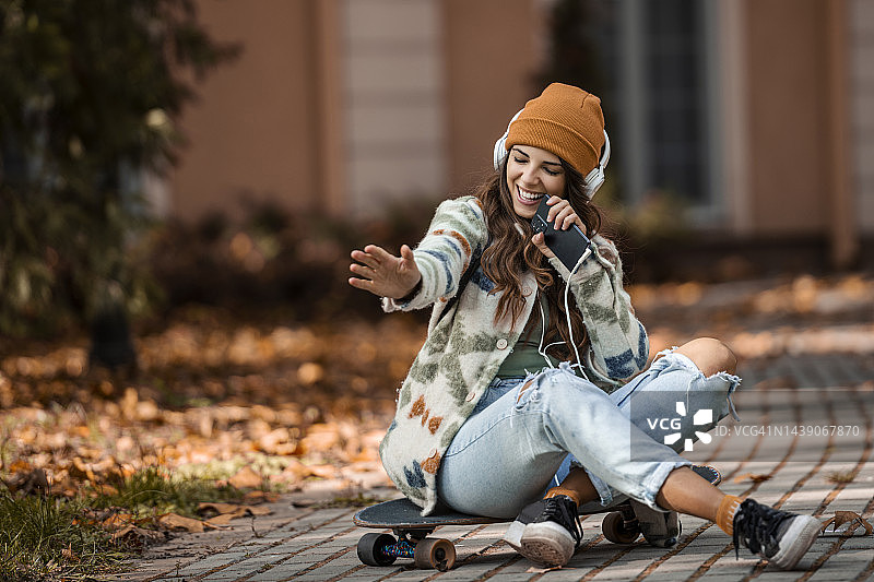 坐在滑板上唱歌的年轻美女图片素材