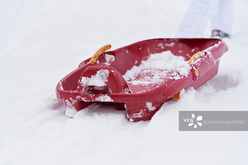 孩子们玩耍后雪地上的红色雪橇：冬季度假概念图片素材