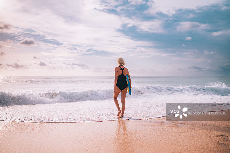 拿着趴板准备入水冲浪的女人图片素材