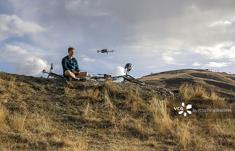 山地自行车手在观景点放松，放飞无人机图片素材
