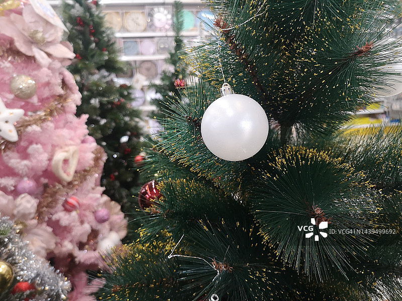 装饰过的绿色圣诞树装饰品有松果白球和树叶在模糊的背景上图片素材