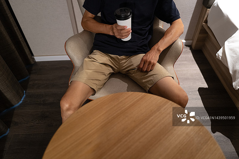 男子坐在座位上手持杯子高角度视图图片素材
