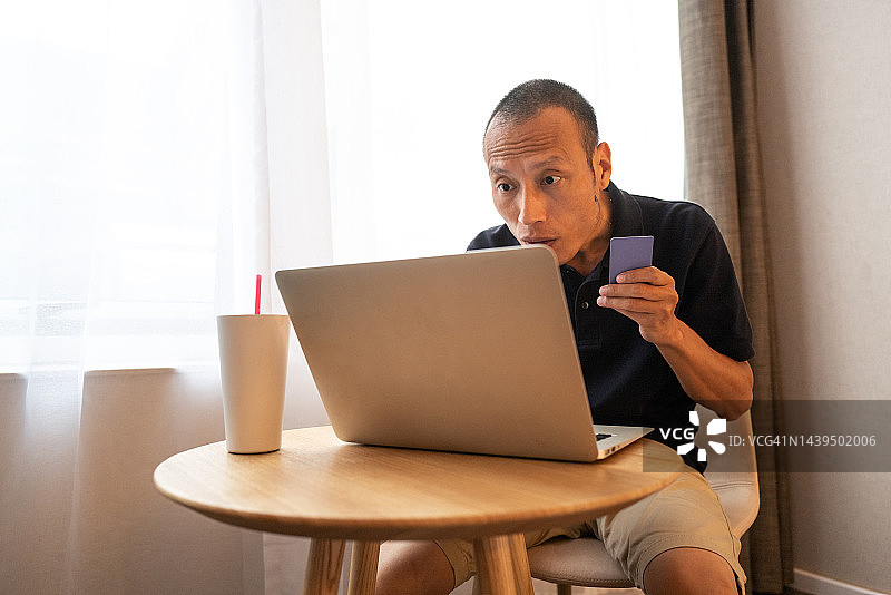 亚洲顾客用笔记本电脑网购，面露惊讶图片素材