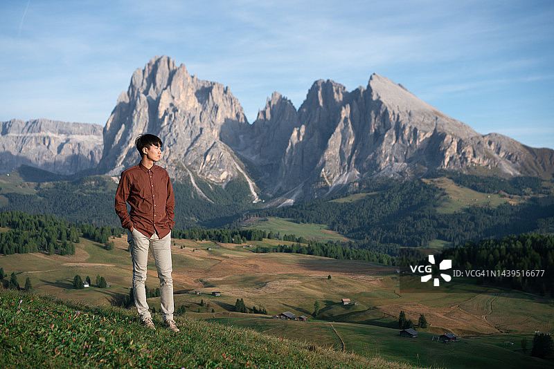 年轻的亚洲男子坐在意大利多洛米蒂山脉的壮丽景色中图片素材