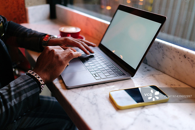 咖啡馆内黑人手部使用笔记本电脑特写图片素材