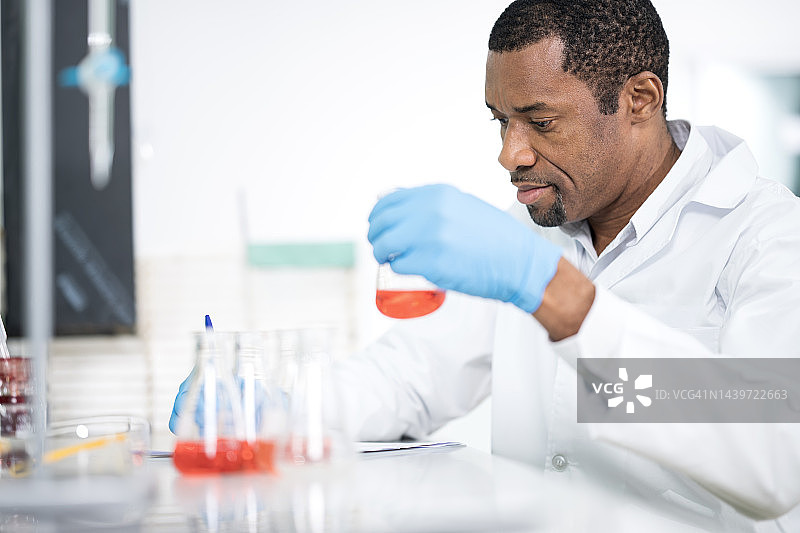 定量数据收集、处理与分析：非裔美国化学家在环境实验室分析化学品样本并在记录簿中记录数据。图片素材