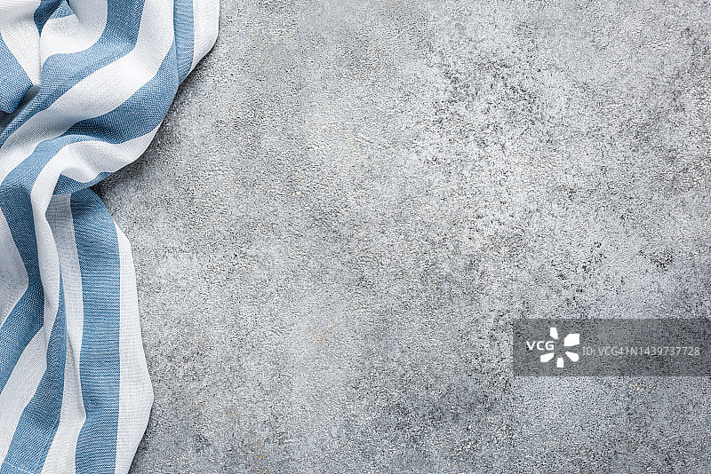 灰色水泥背景上的蓝色条纹厨房用巾图片素材