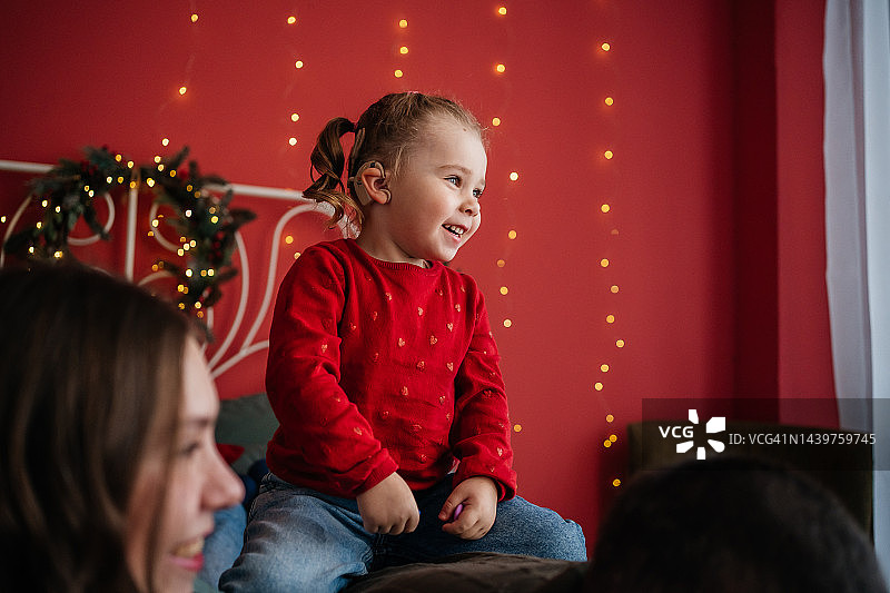 圣诞节，带着人工耳蜗的婴儿在床上和妈妈玩耍图片素材