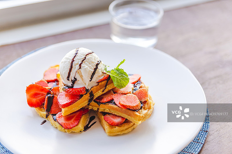 白色盘子里的草莓冰淇淋、巧克力酱和华夫饼图片素材