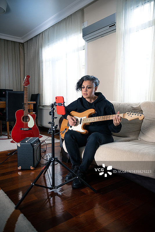 年轻女子在社交媒体上的个人音乐频道上弹奏电吉他并唱歌图片素材