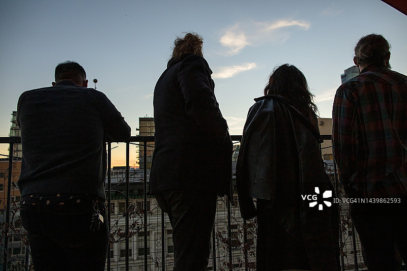 从市中心阳台看日落的朋友们的局部剪影图片素材