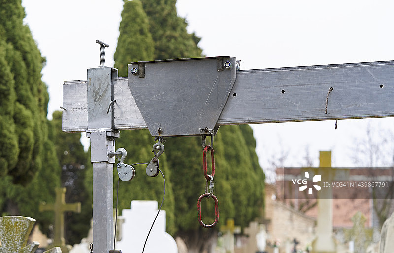 带滑轮的墓地用金属杆或结构，背景是生锈的链条和十字架形状的墓碑图片素材