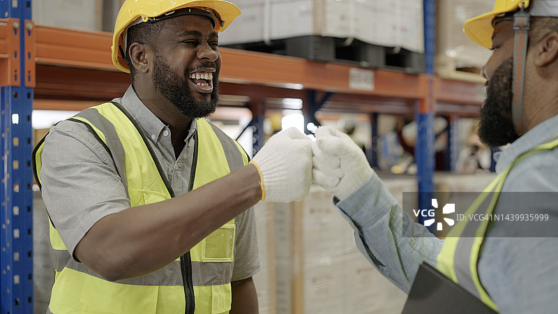 仓库工人在早上开始工作时快乐地击拳。图片素材