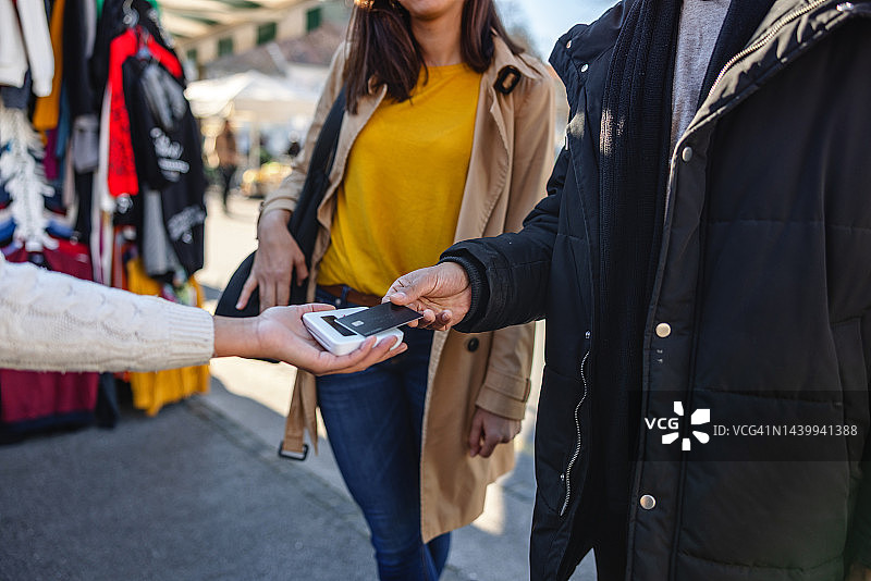 西班牙裔男人在街头市场用信用卡购买服装图片素材