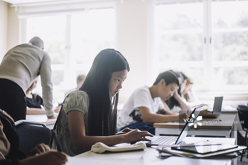 在学校教室里用笔记本电脑进行电子学习的初中女生图片素材
