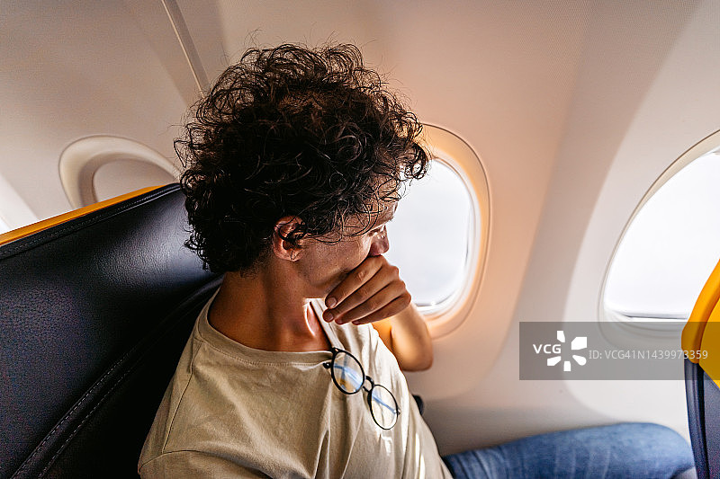 害怕的男乘客看着飞机窗外图片素材