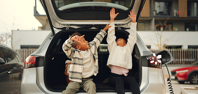 兴奋的兄弟姐妹等待汽车充电图片素材
