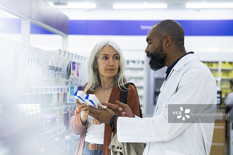 药房里，中年女顾客在非洲裔美国男销售员的帮助下购物图片素材