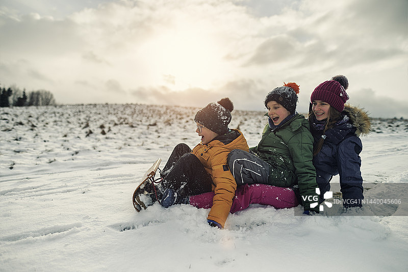 孩子们在冬日山坡上一起玩雪橇图片素材