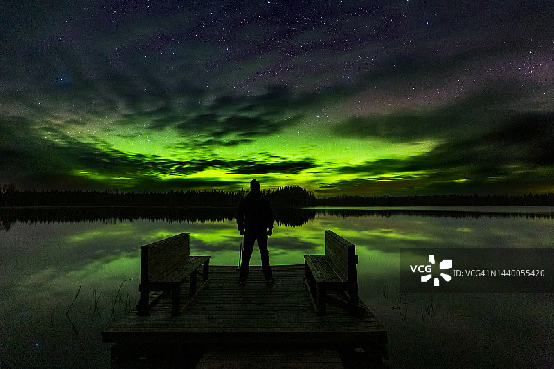 男人在芬兰卢汉卡湖边欣赏北极光图片素材