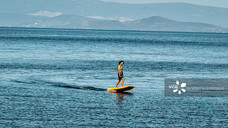 男子在湖面或海上冲浪，脚踩水翼冲浪板图片素材