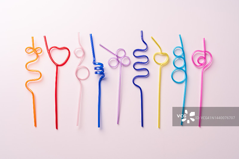 排列在粉红色背景上的一系列彩色塑料吸管图片素材