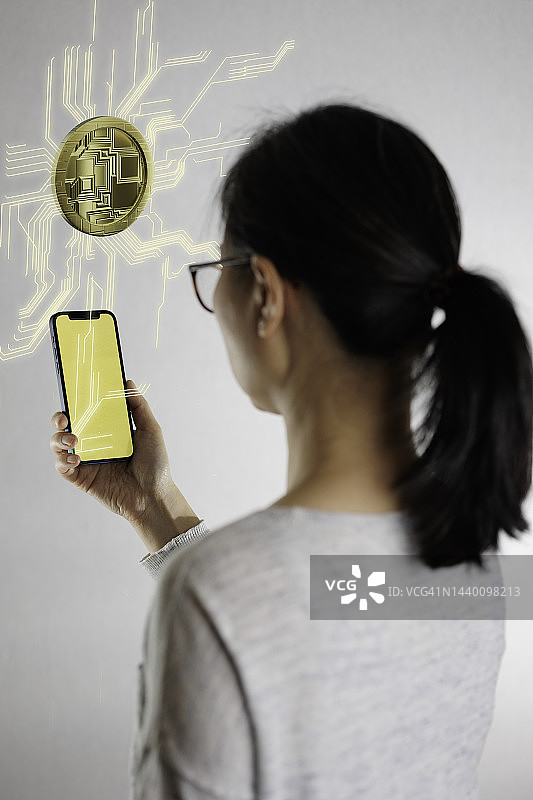 手持移动设备，带有加密货币效果的中年亚洲女人图片素材