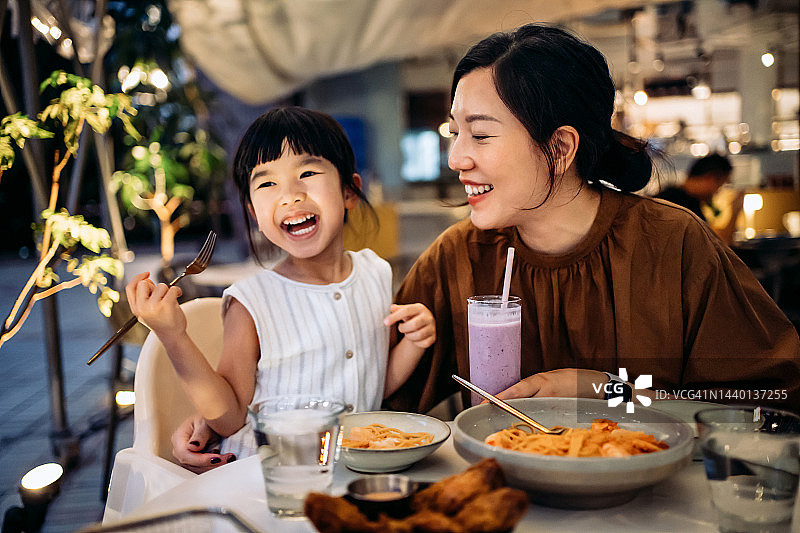 快乐的年轻亚洲家庭在户外餐厅共进晚餐图片素材