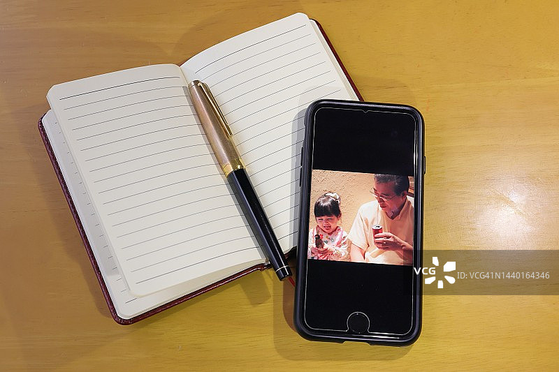 回忆，木桌上的钢笔、记事本和智能手机图片素材