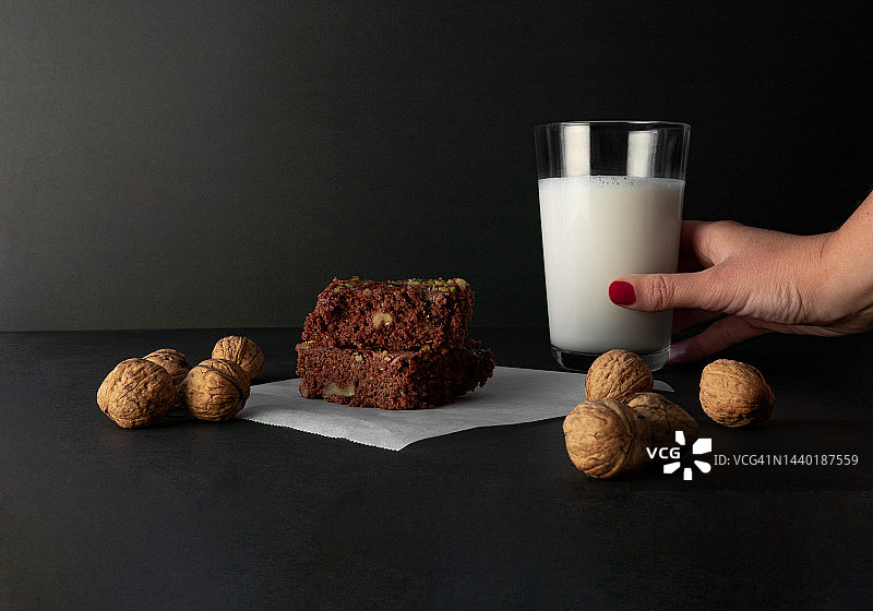 女人手持植物巧克力布朗尼、非乳制奶和核桃特写图片素材