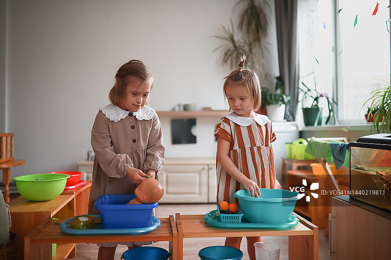 患有唐氏综合症的女孩在盆中清洗娃娃图片素材