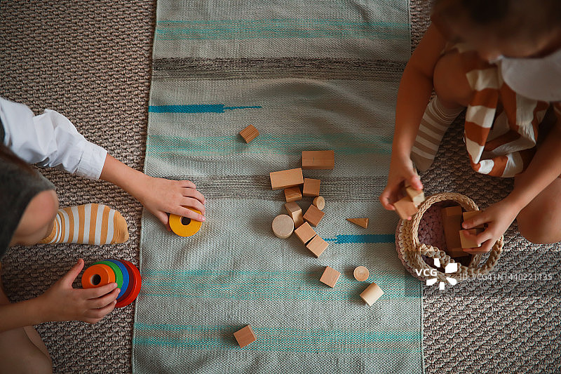 两个孩子在地垫上玩木制玩具，顶视图，幼儿园蒙台梭利图片素材