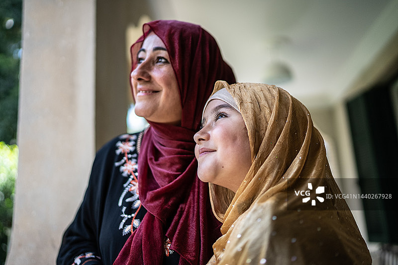 在家中阳台上眺望远方的快乐母女图片素材