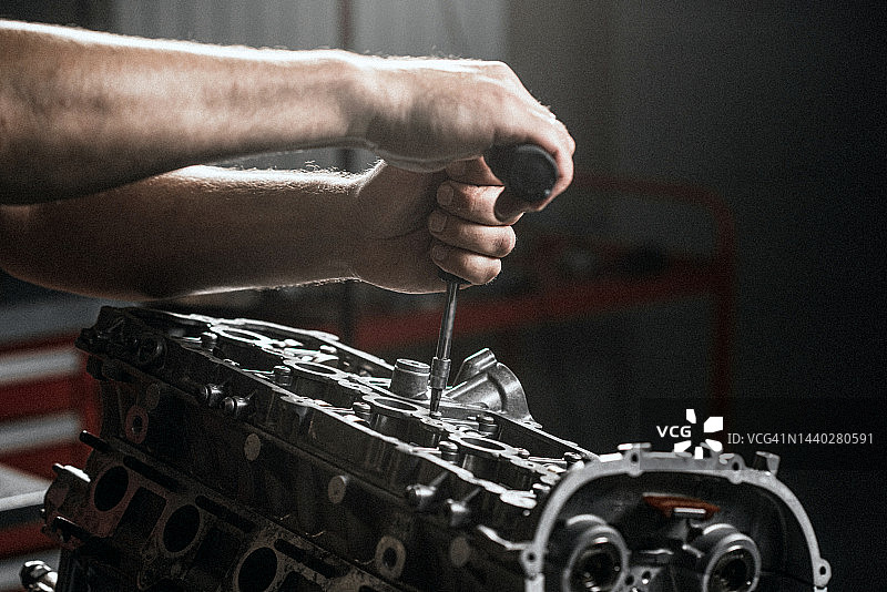 修理发动机，机械师在修理厂用螺丝刀图片素材