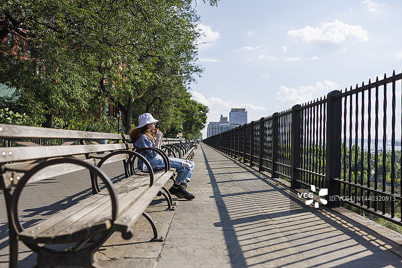 年轻女子坐在布鲁克林高地长廊的板凳上等人图片素材