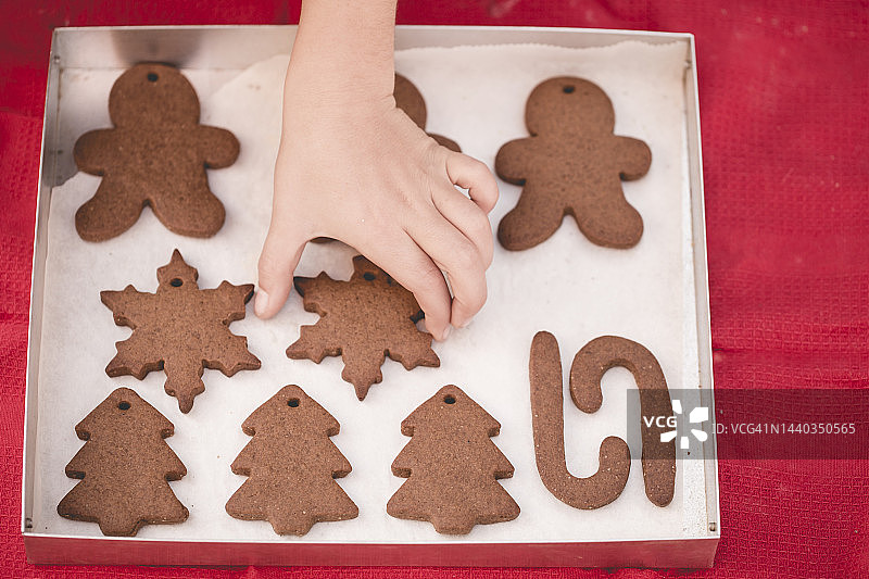 孩子的手够向新鲜出炉的自制雪花姜饼饼干俯视图图片素材