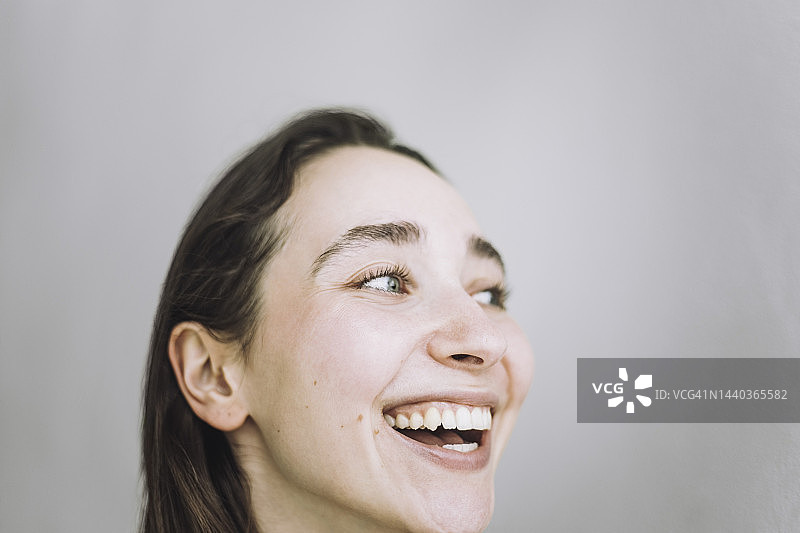 快乐的女时装设计师在灰色背景下眺望远方图片素材