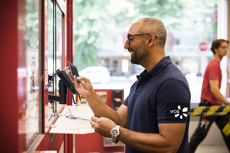 微笑的男性顾客在五金店收银台进行在线支付的侧视图图片素材